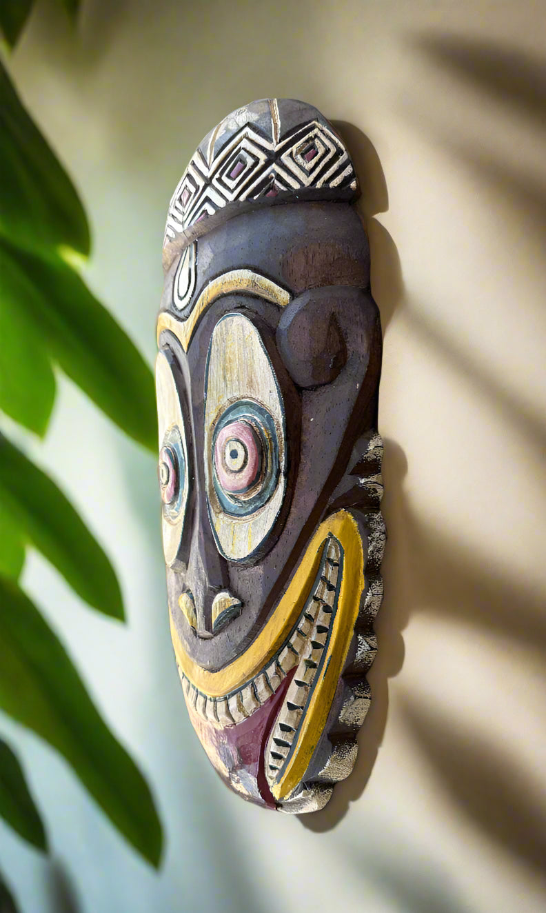 Colorful tribal carved wooden mask with geometric patterns on a wall